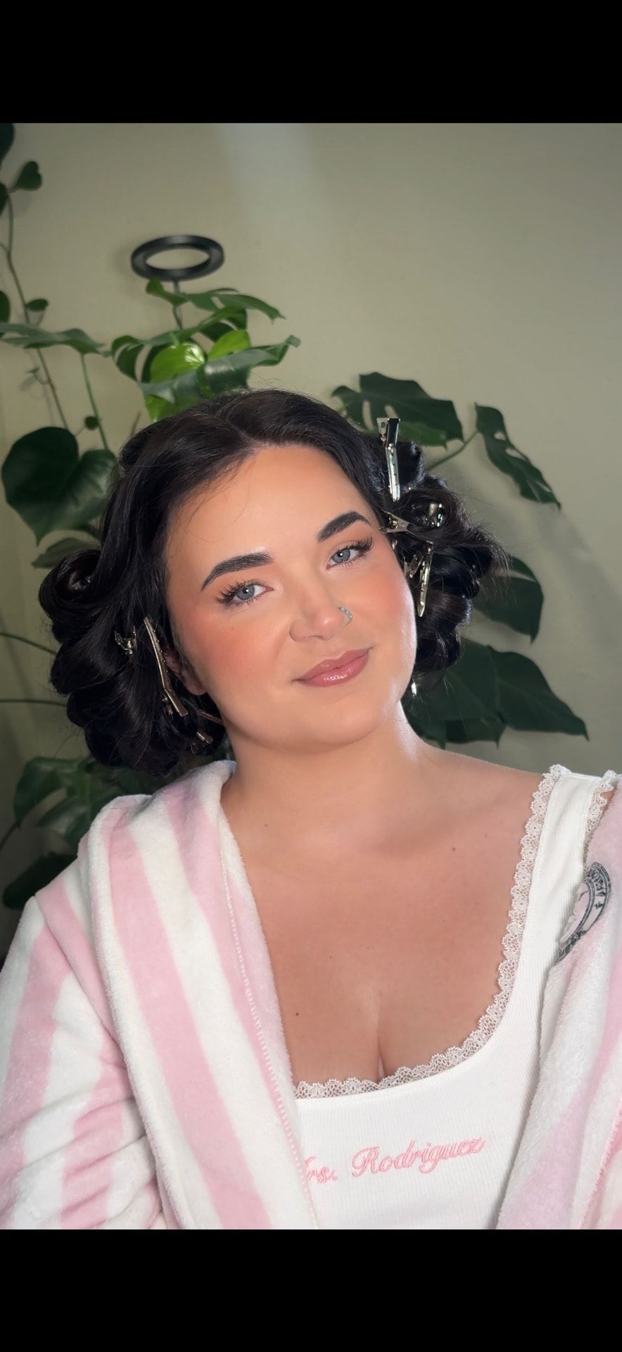 Bride getting ready in a striped robe with soft glam bridal makeup by Maddy Donohue